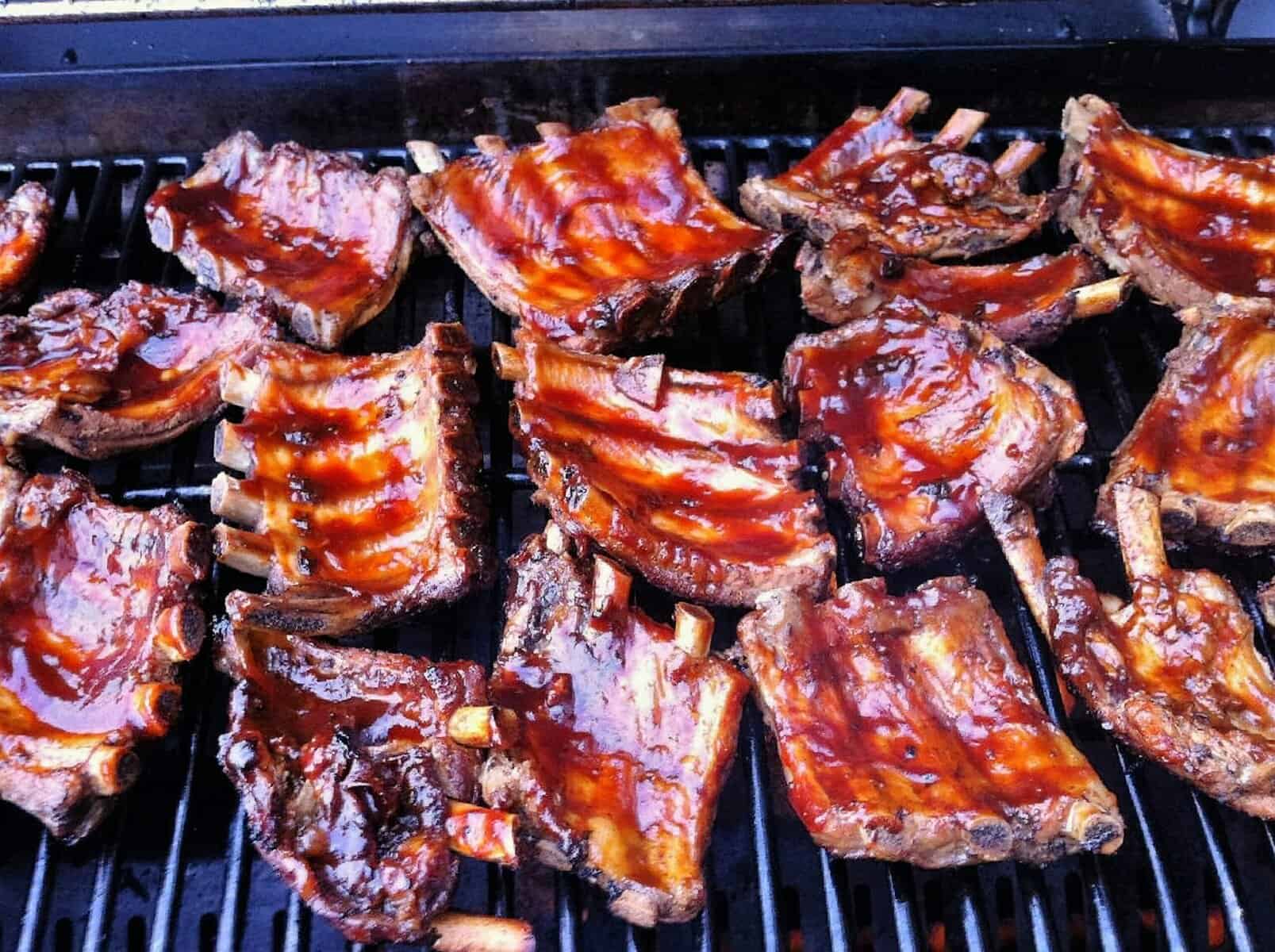 Spareribs mit BBQ-Glasur auf Grillrost über glühender Kohle
