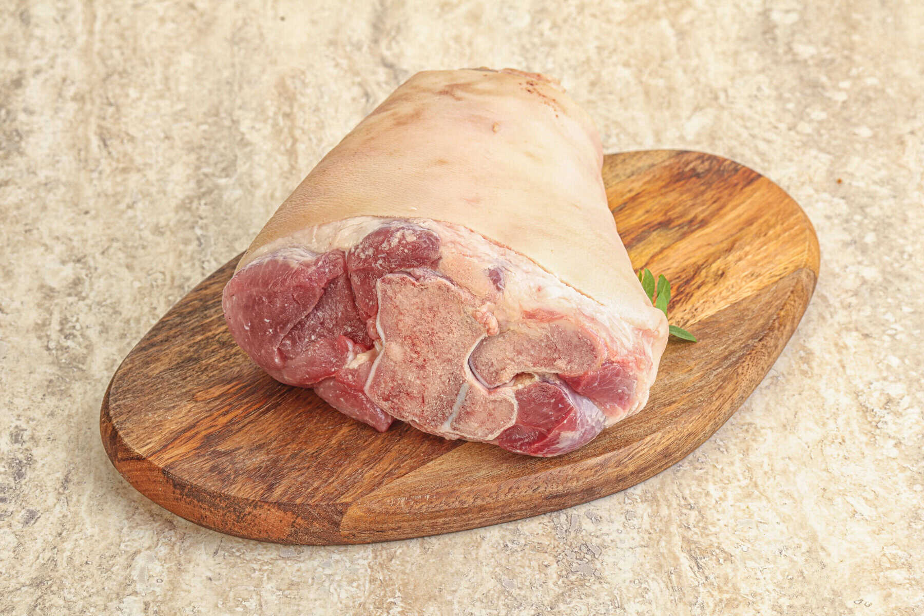 Rohe Schweinshaxe auf Holzbrett.